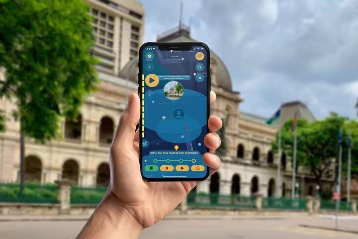Self-guided Brisbane dark history walking tour app on smartphone in front of iconic Queensland Parliament House